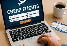 Person searching for cheap flights on a laptop with airplane tickets and coffee